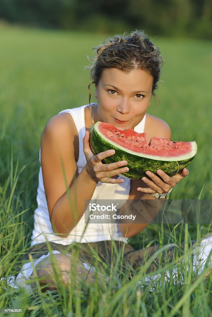 Retrato de una joven mujer comiendo sandía en verde hierba - Foto de stock de Cara humana libre de derechos