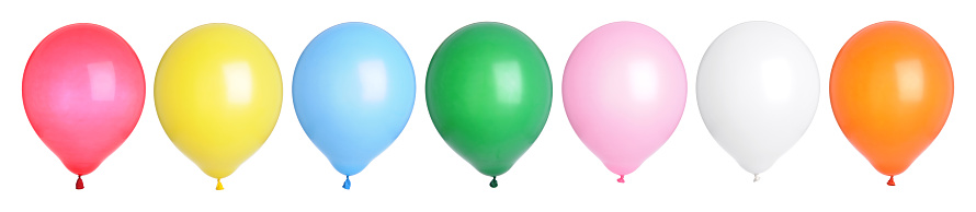 Multi-colored helium ballons collect along the ceiling of a banquet hall.