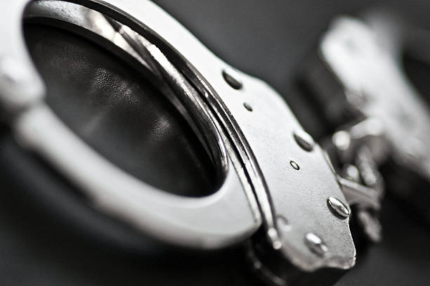 Black and white close-up of silver handcuffs closeup on handcuffs. selective focus. cuff stock pictures, royalty-free photos & images