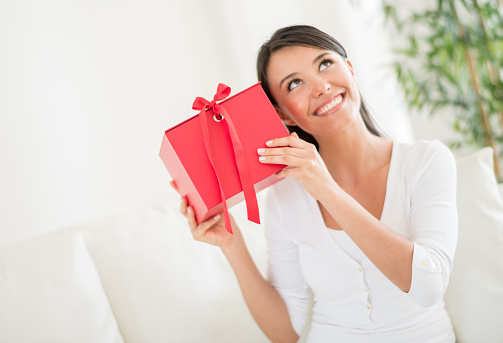 Happy woman at home guessing what she got for a gift