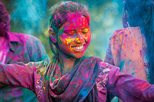 Young woman covered in colored dye enjoying Holi festival in Jaipur, India.