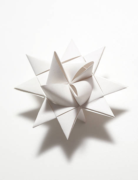 Origami ring made of linked colorful paper sheets lays on a white wooden table, close up photo with selective soft focus