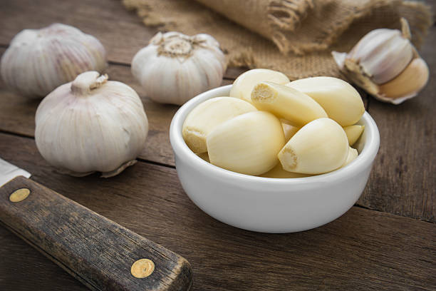 Peeled garlic in bowl Peeled garlic in bowl kitchen knife photos stock pictures, royalty-free photos & images