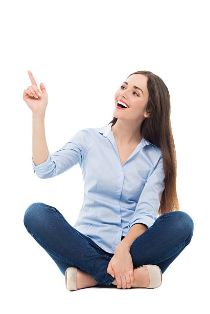 istock Young woman sitting and pointing up 471176180