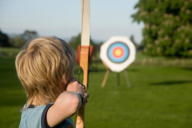 Archery Boy taking part in the sporting activity of archery.  Taking aim at the target archery photos stock pictures, royalty-free photos & images