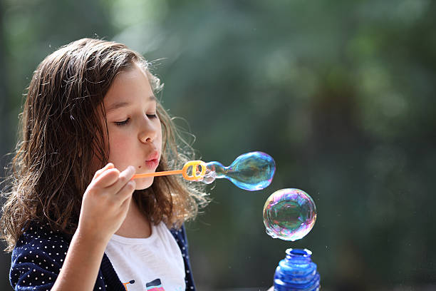 istock Young girl blowing bubbles 471180157