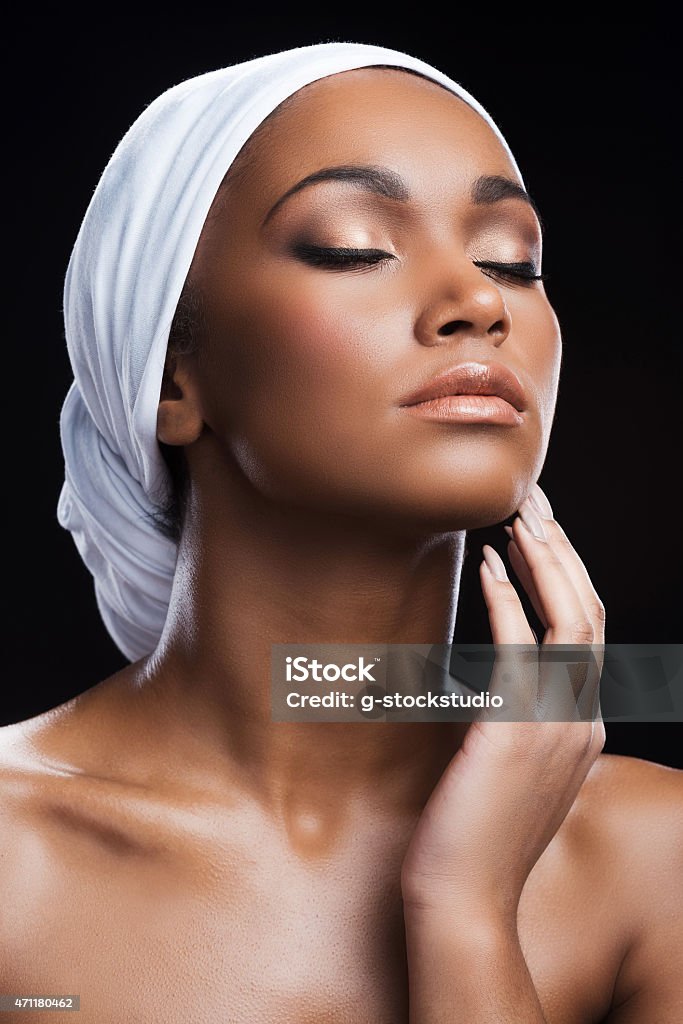 Fresh and beautiful. Beautiful African woman wearing a headscarf and keeping eyes closed while standing against black background 20-29 Years Stock Photo