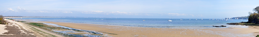 Studland Bay in Dorset. Bournemouth  in the distance, Old Harry Rocks on the right. People on the beach, boats out to sea.