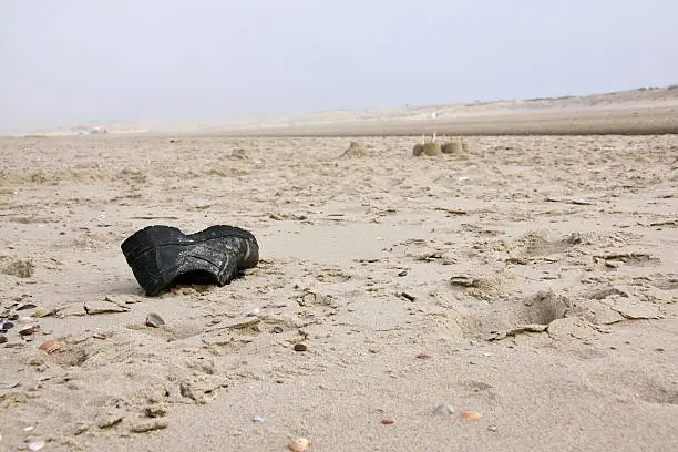 Empty shoe on the beach of Vrouwenpolder in the Netherlands. Focus on shoe. Slightly foggy background. 