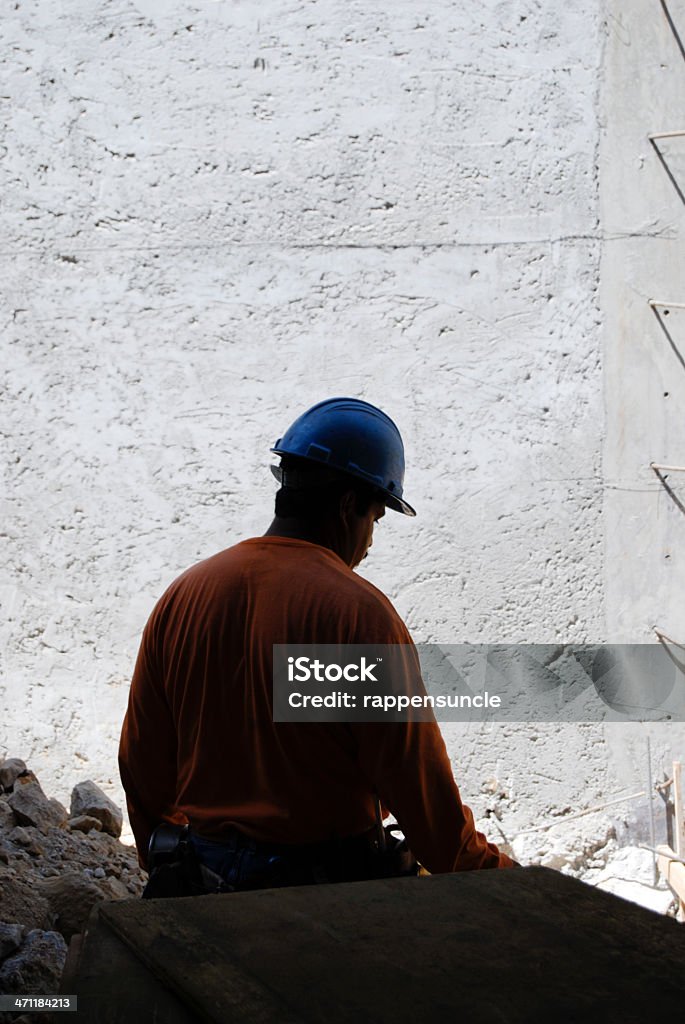 Construction worker Silhouette of a construction worker with a gray concrete wall background. Blue-collar Worker Stock Photo