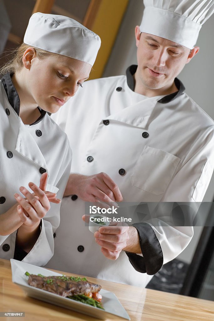 Culinary School A professional chef teaching a culinary student proper techniques in a kitchen environment.  Shallow dof Adult Stock Photo