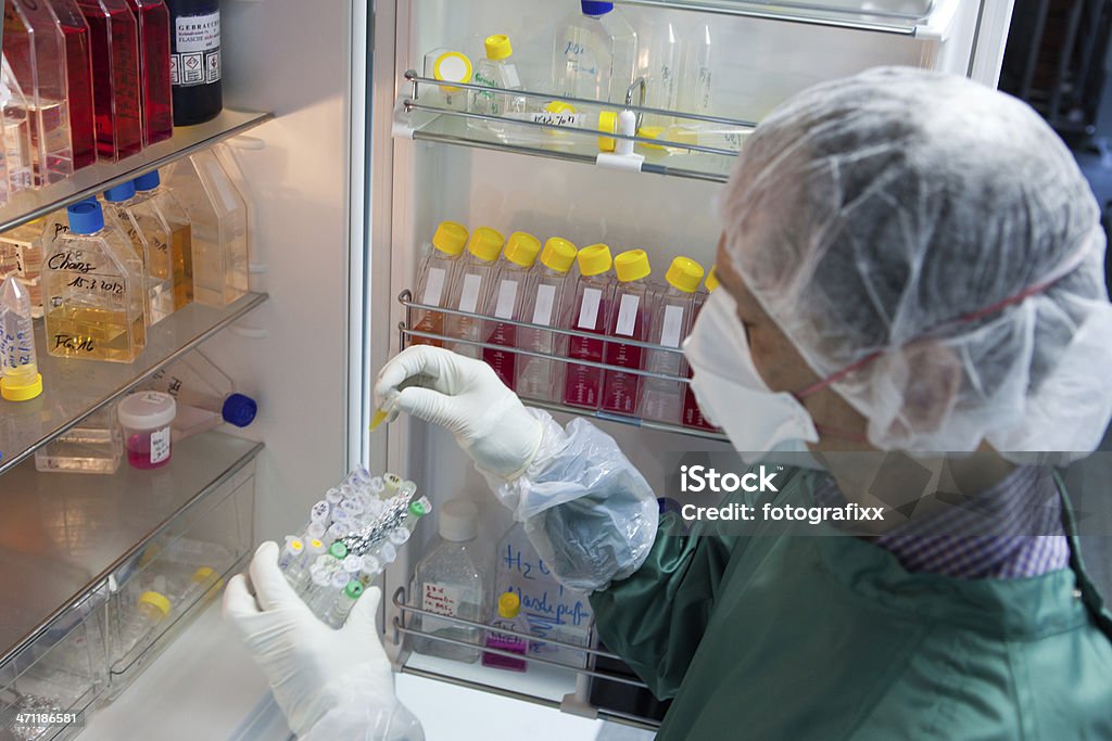 scientist takes a sample from the refrigerator In his lab a scientist takes a sample from the refrigerator. Refrigerator Stock Photo