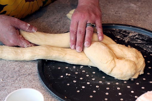 A woman braiding challah (a Jewish braided bread).