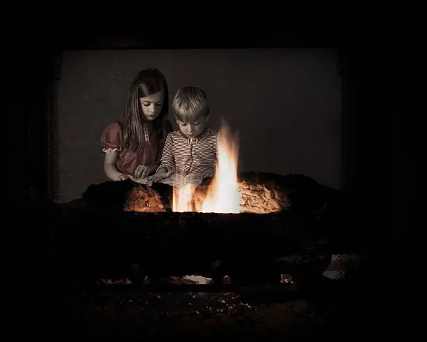 Two children reading bedtime stories by the glow of  the fireplace.  Please note: sepia toning and a bit