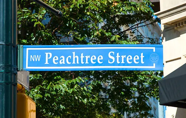 Peachtree Street Sign in Atlanta, with trees and downtown buildings in the background.  Peachtree Street is Atlanta's "main street", being the spine of inner city Atlanta, with Downtown, Midtown, and Buckhead centered on it.  