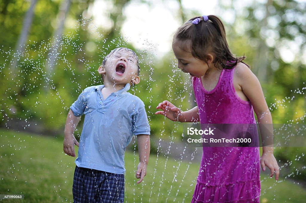 Sprinkler Drinkers children drink sprinkler / while sprinkler drenches children / it's summertime fun Child Stock Photo