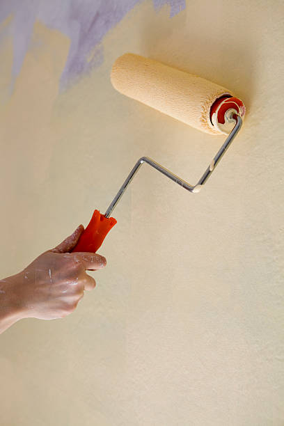 istock Caucasian Hand Painting Yellow Interior Wall with Roller, Copy Space 471191207