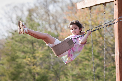 Beautiful young girl swinging on playground equipment