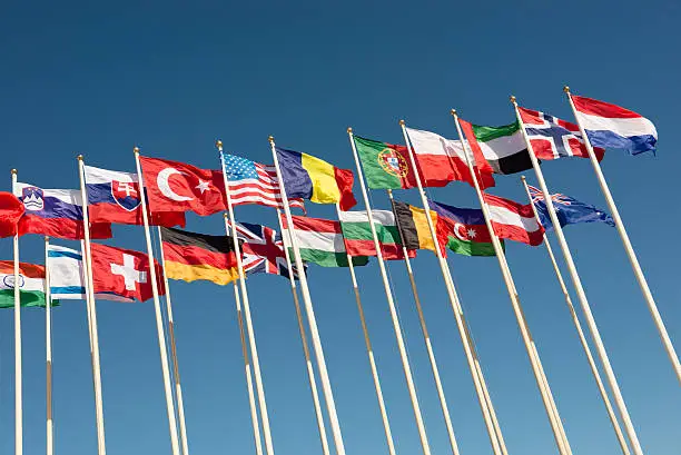 flags of different countries on flagpoles fluttering in the wind