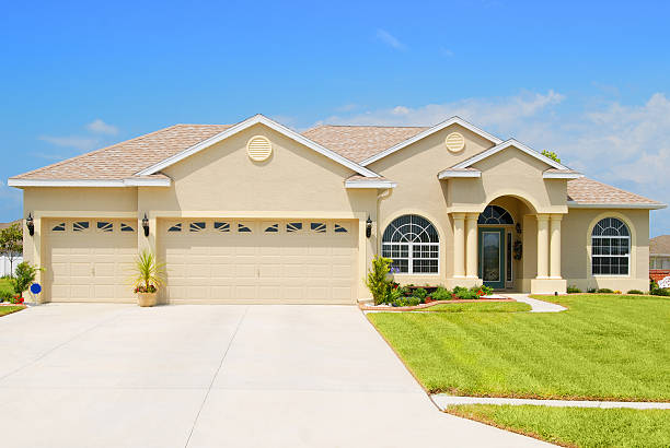 istock Large custom home with beige exterior and green lawn 471194271