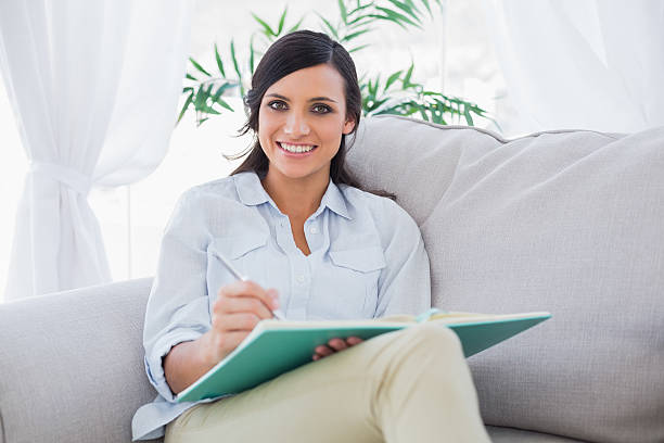 istock Smiling gorgeous brunette writing while sitting on the sofa 471195234