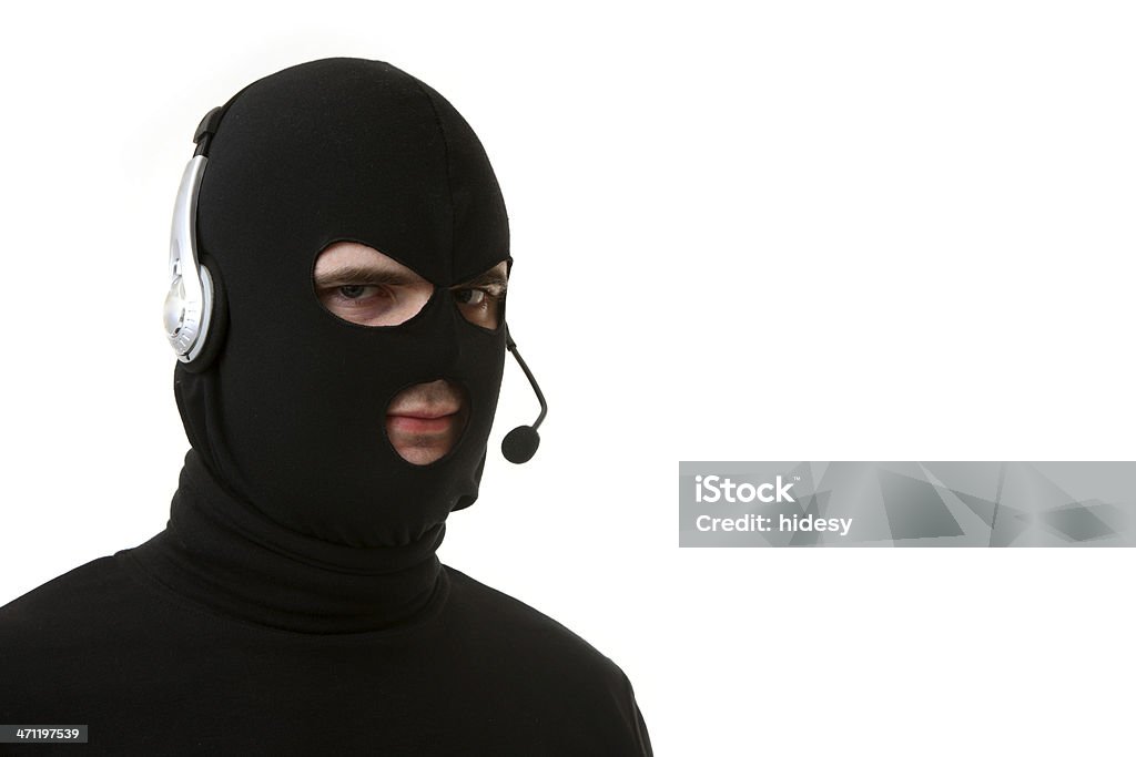 Criminal or Thief on White with Headset Criminal or thief in a balaclava and black clothes on a white background with headset Telephone Stock Photo