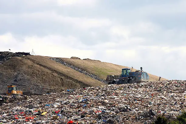 Large landfill site with solid waste being unloaded and spread. This landfill produces enough methane gas to supply power to thousands of homes.