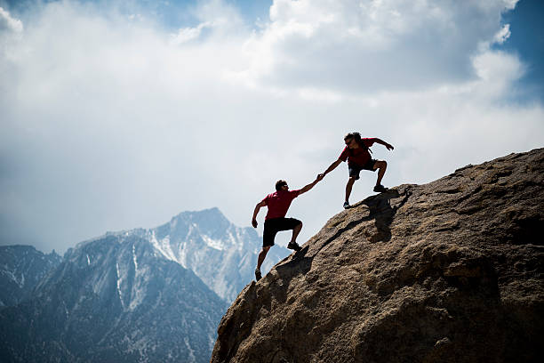 Helping hikers One climber helping another to the summit of a giant boulder  on top of stock pictures, royalty-free photos & images