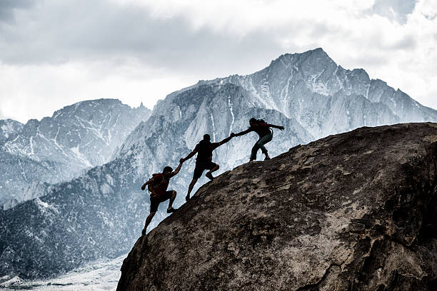 three friends helping Three friends out rock climbing, helping each other in a dramatic setting clambering stock pictures, royalty-free photos & images