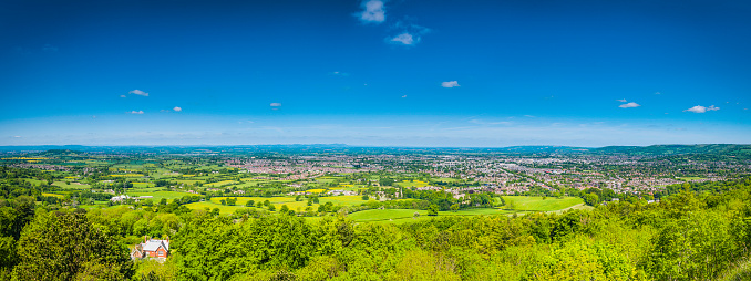 Deep blue panoramic summer skies over the picturesque green patchwork quilt landscape of pasture and meadows surrounding the country town of Cheltenham Spa, Gloucestershire, UK. ProPhoto RGB profile for maximum color fidelity and gamut.