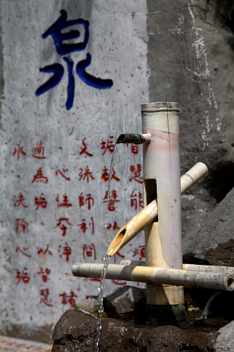 Bamboo fountain in a Chinese garden,the large blue  Chinese Script means \
