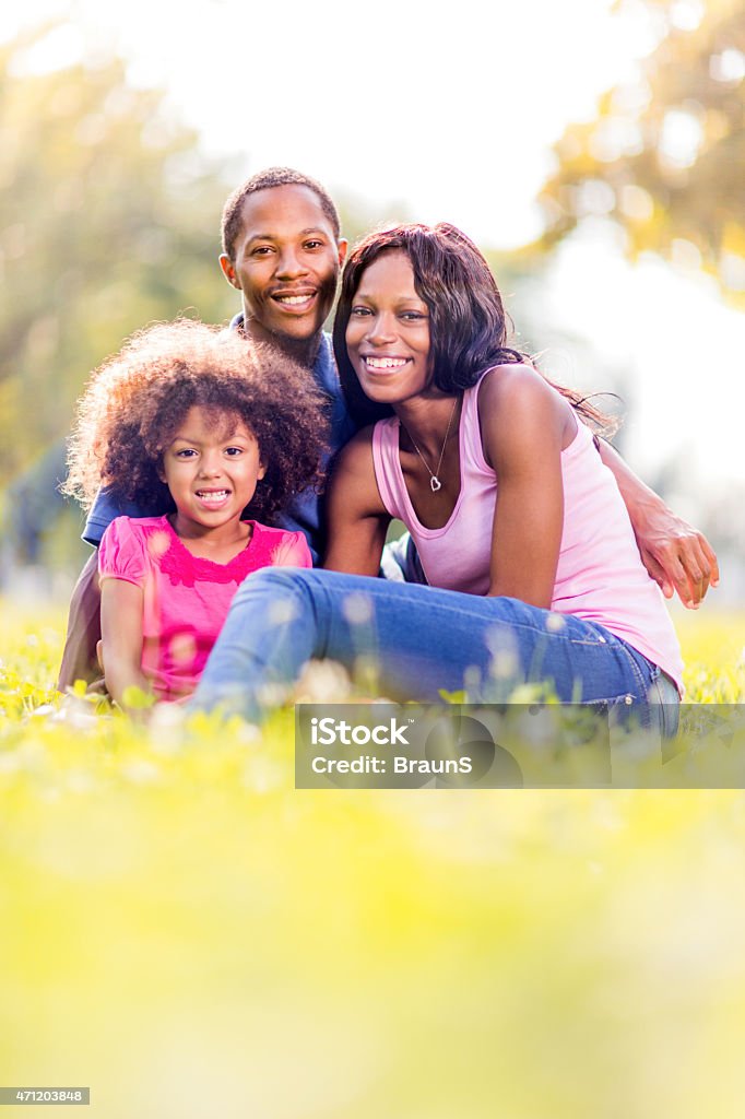Happy African American family enjoying a day in nature. Young African American parents enjoying with their little girl in the park and looking at the camera. Child Stock Photo