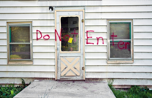 a front door to a home that has been condemned after a flood, spraypainted 