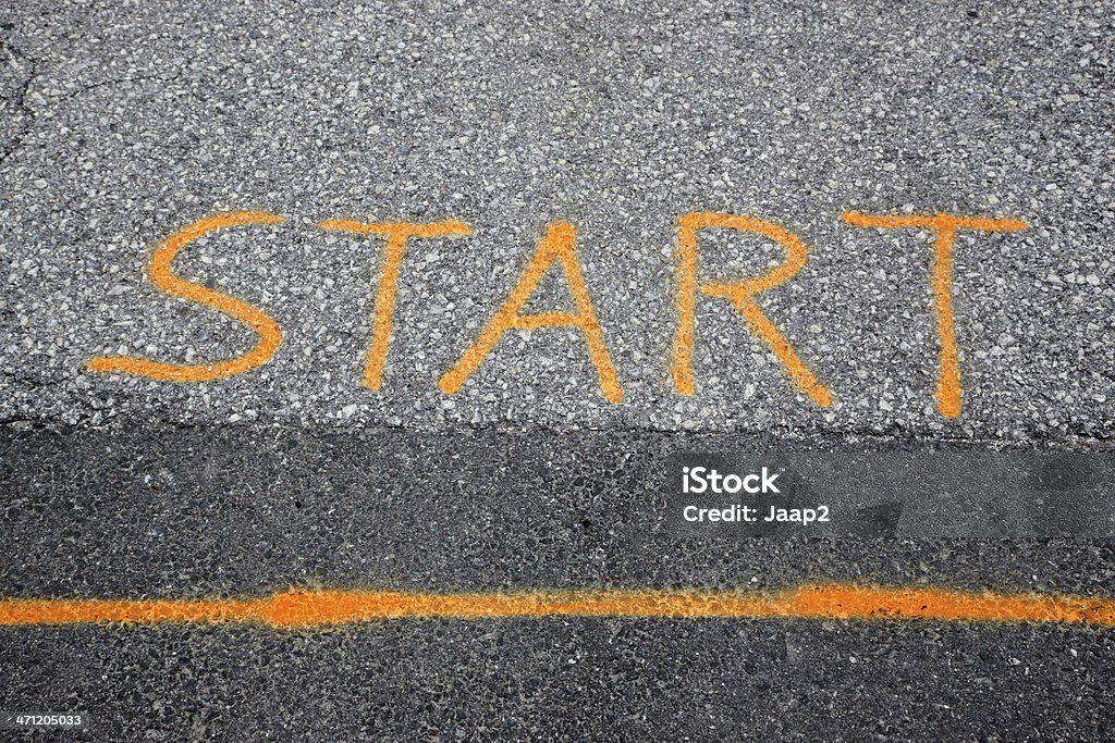 Linea di partenza con il testo "START" come dipinto su strada asfaltata - Foto stock royalty-free di Arancione