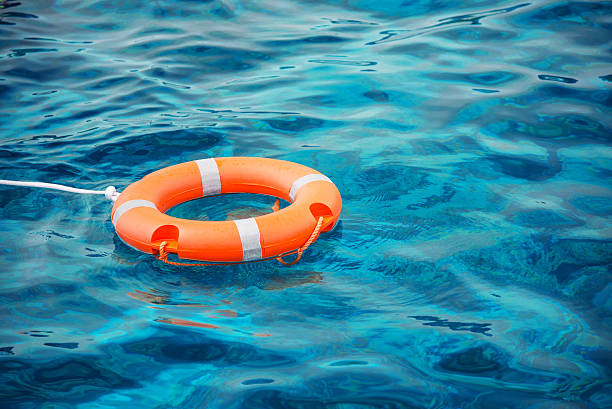 Lifebuoy in a stormy blue sea Lifebuoy in a stormy blue sea swimming protection stock pictures, royalty-free photos & images