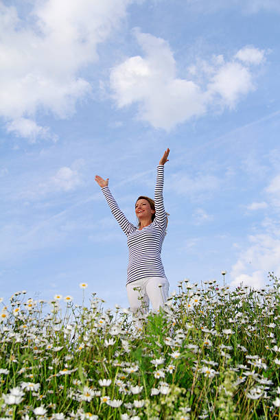 istock Woman with stretched arms in flower field 471209742