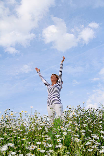 istock Woman with stretched arms in flower field 471209746