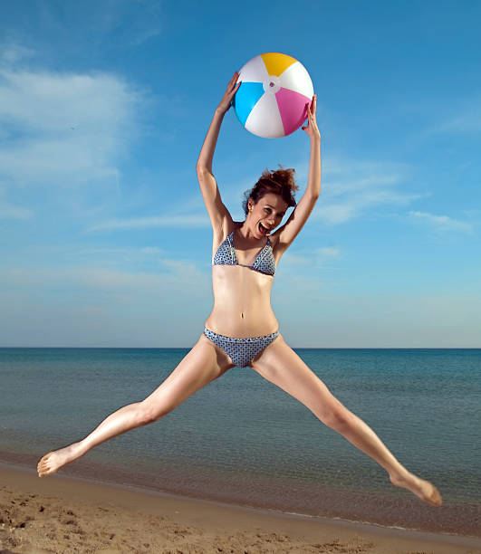 Fashion model with beach ball Fashion model jumping with beach ball healthy slim fit in bikini stock pictures, royalty-free photos & images