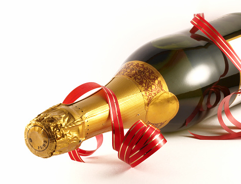 An unopened champagne bottle with a red ribbon isolated on white