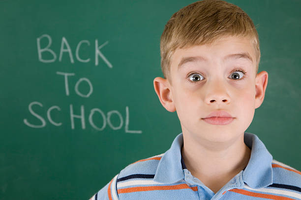 istock Young boy standing in front of chalkboard 471212269