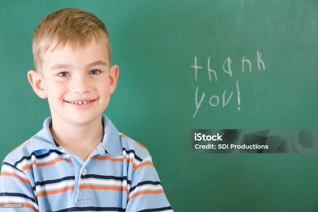 Aluno de Primário posando depois de escrever "Obrigado" em escola Chalkboard - Foto de stock de Acontecimentos da Vida royalty-free