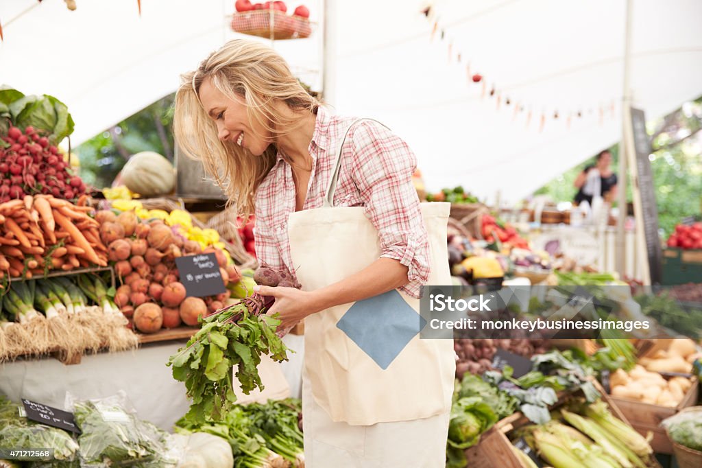 Female Customer Shopping At Farmers Market Stall Female Customer Shopping At Farmers Market Stall, Smiling Market - Retail Space Stock Photo