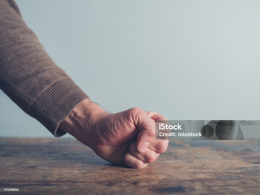 Man slamming his fist on table Closeup on a man slamming his fist on a wooden table Table Stock Photo