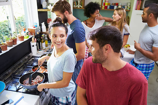 Group Of Friends Cooking Breakfast In Kitchen Together Group Of Friends Cooking Breakfast In Kitchen Together roommate stock pictures, royalty-free photos & images