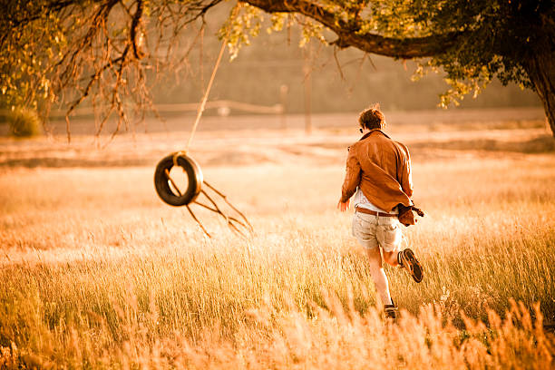 junger mann läuft in richtung eine seilschaukel - men swing rope swing tire stock-fotos und bilder