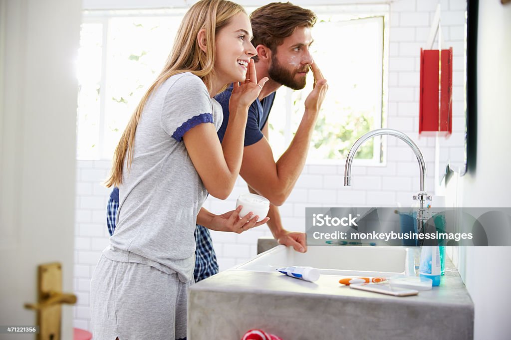 Couple In Pajamas Putting On Moisturizer In Bathroom Skin Care Stock Photo