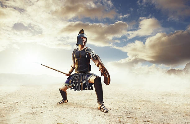 Ancient warrior in a typical black costume holding a spear Ancient Greek rome warriors fighting with swords and shields in the combat on sand and dust. Achilles and Hector fighting at Troy gladiator stock pictures, royalty-free photos & images