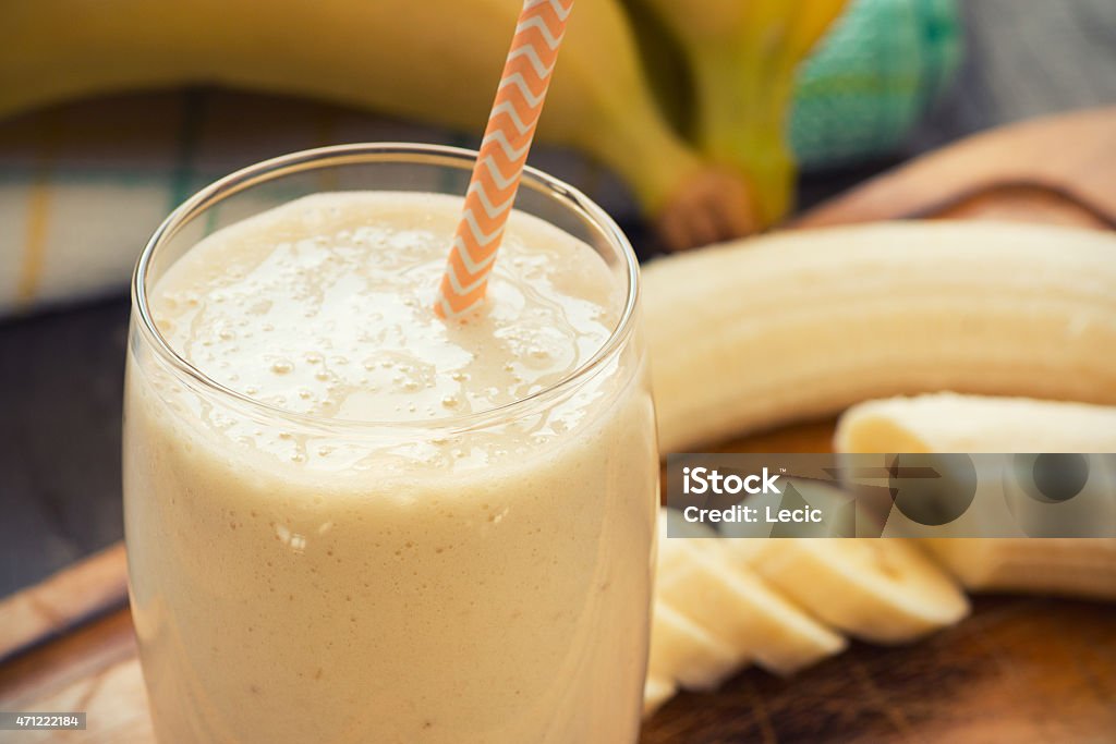 Fresh-made glass of banana smoothie with straw on wood Fresh made Banana smoothie on wooden background Banana Smoothie Stock Photo