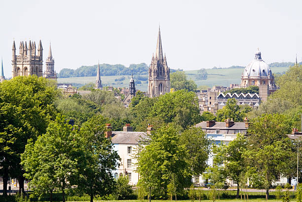 Spires of Oxford The often referred to ‘dreaming spires’ spires and towers of the skyline of the University city of Oxford pierce the leafy parkland foliage. Matthew Arnold dubbed Oxford as the "City of Dreaming Spires" based on the architecture of the world famous University buildings. The nearest building on the left is Magdalen College Tower, and the church with the round spire immediately behind was formerly All Saints Church, but is now deconsecrated and houses the library of Lincoln College. The Church of St. Mary the Virgin is in the centre and the distinctive dome of The Radcliffe Camera building is on the right. Good copy space. radcliffe camera stock pictures, royalty-free photos & images