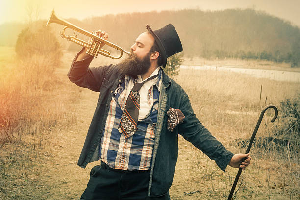 Man in formal suit, tie, sunglasses, bowler hat, holding trumpet, on country road